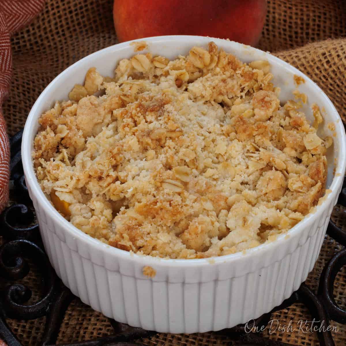 an individual peach crisp in a white ramekin.