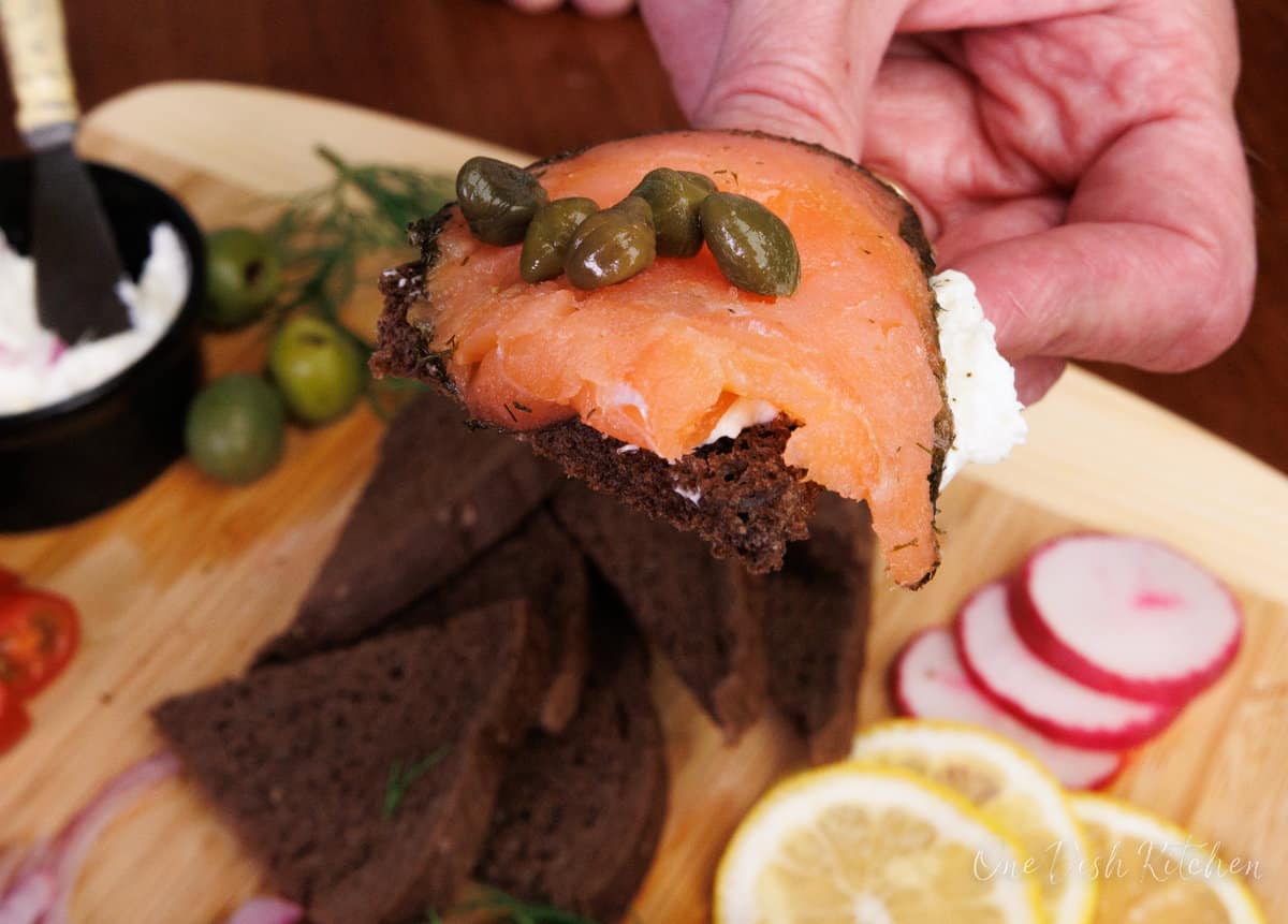 pumpernickel bread topped with cream cheese, salmon, and capers.