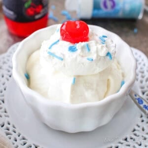 a single serving of vanilla ice cream in a bowl with a cherry on top.