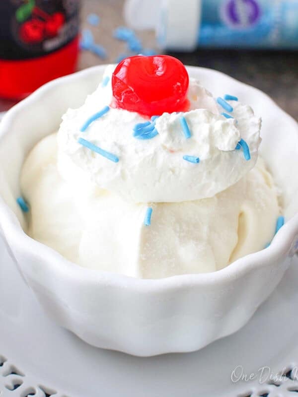 a single serving of vanilla ice cream in a bowl with a cherry on top.