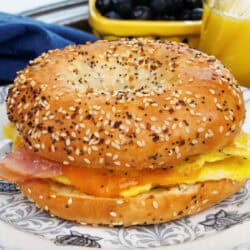 a high protein breakfast bagel with eggs, ham and cheese on a plate.