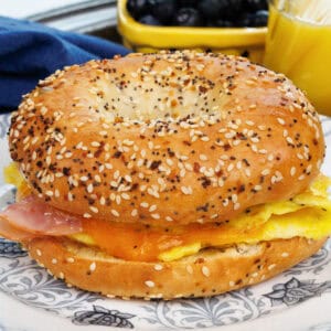 a high protein breakfast bagel with eggs, ham and cheese on a plate.