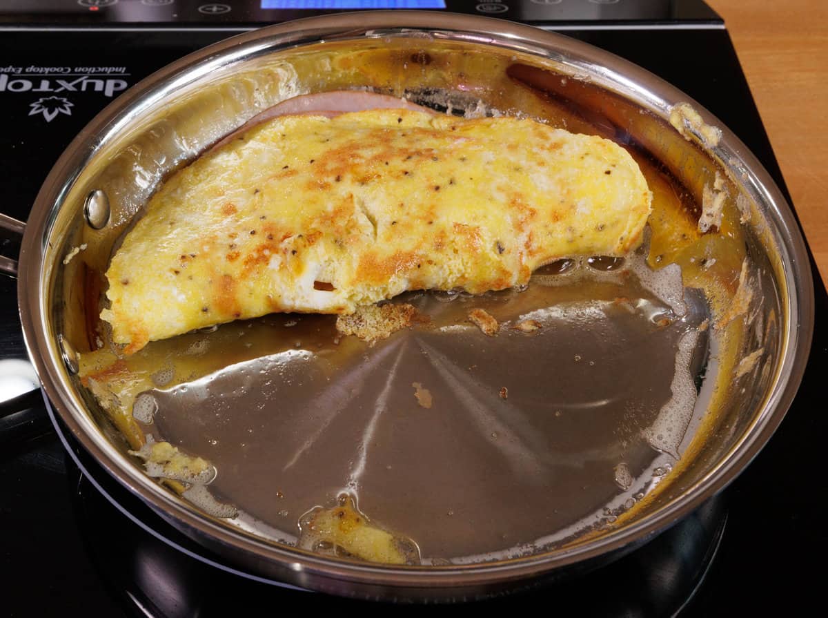 a ham and cheese omelet in a skillet.