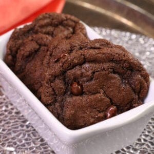 5 cookies in a mini white loaf pan stacked side by side next to an orange napkin.