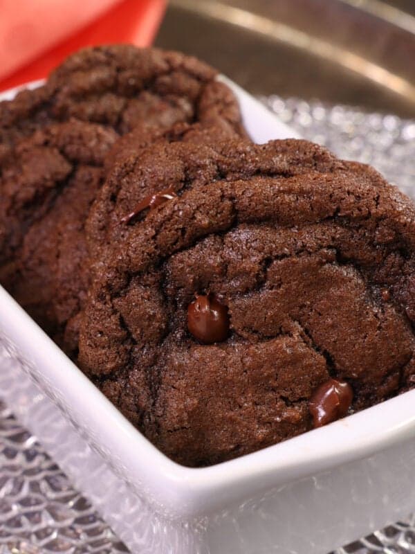 5 cookies in a mini white loaf pan stacked side by side next to an orange napkin.