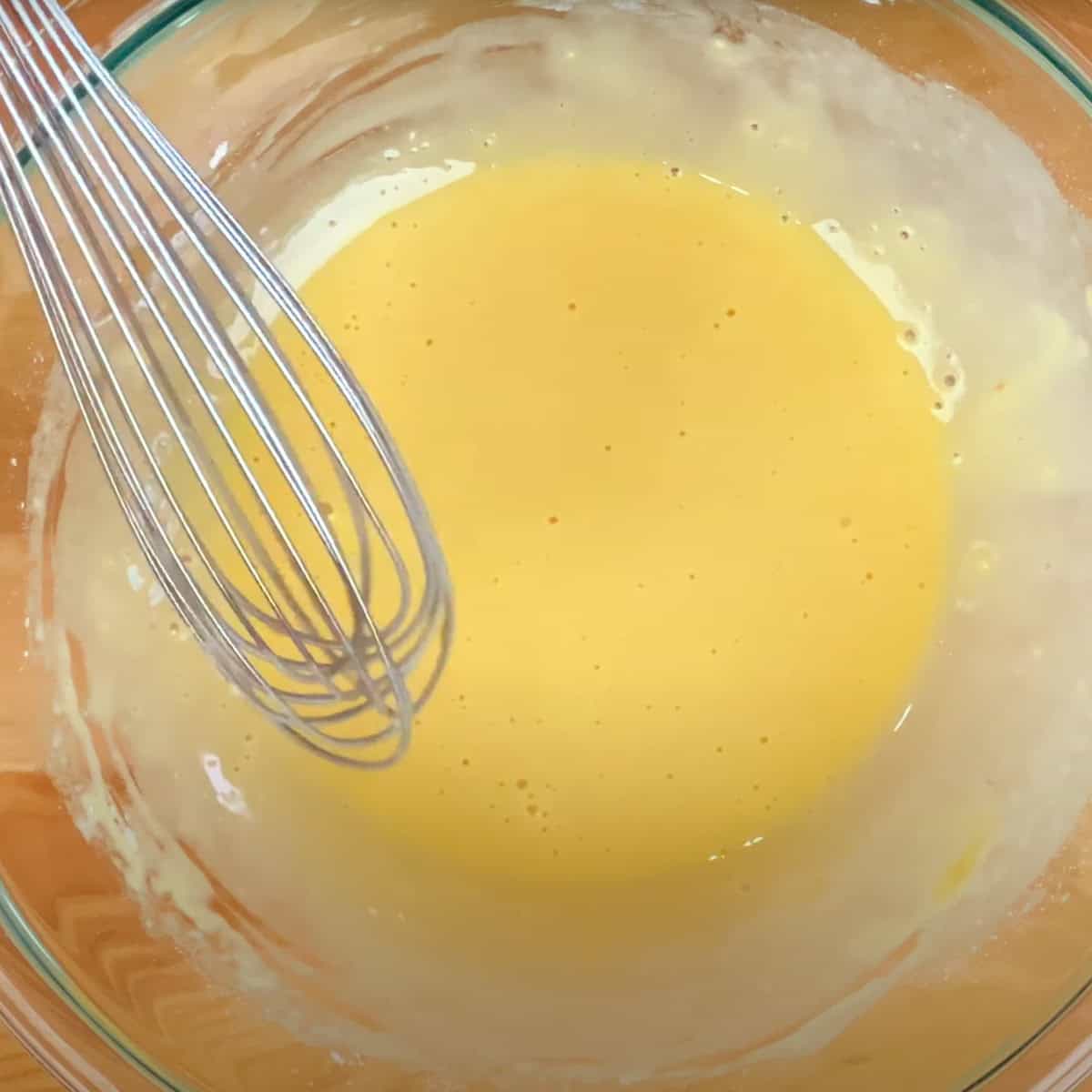an egg, milk, vanilla sugar, and flour in a mixing bowl for dutch baby batter.