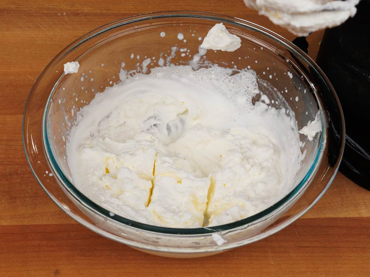homemade whipped cream in a bowl next to an electric mixer