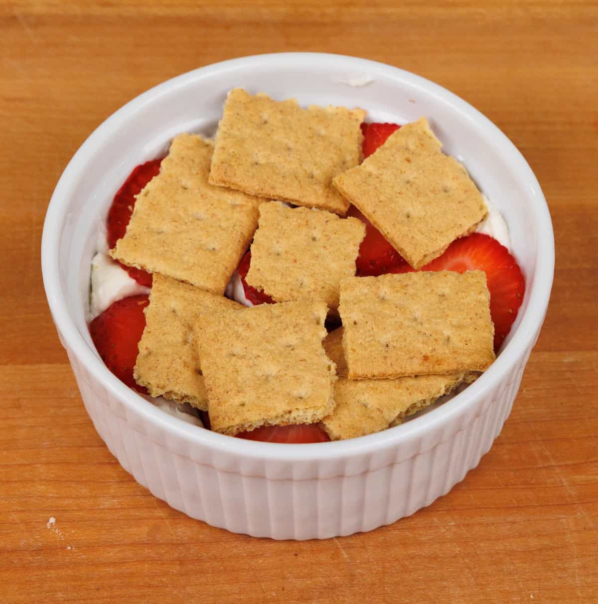 a layer of graham crackers covering strawberries and cream in a small baking dish.
