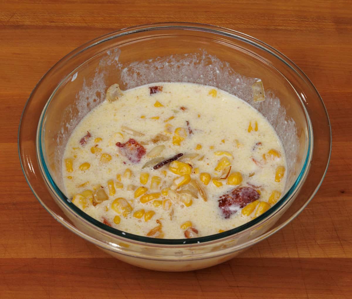 corn, bacon, onions, milk, sour cream, and butter in a mixing bowl