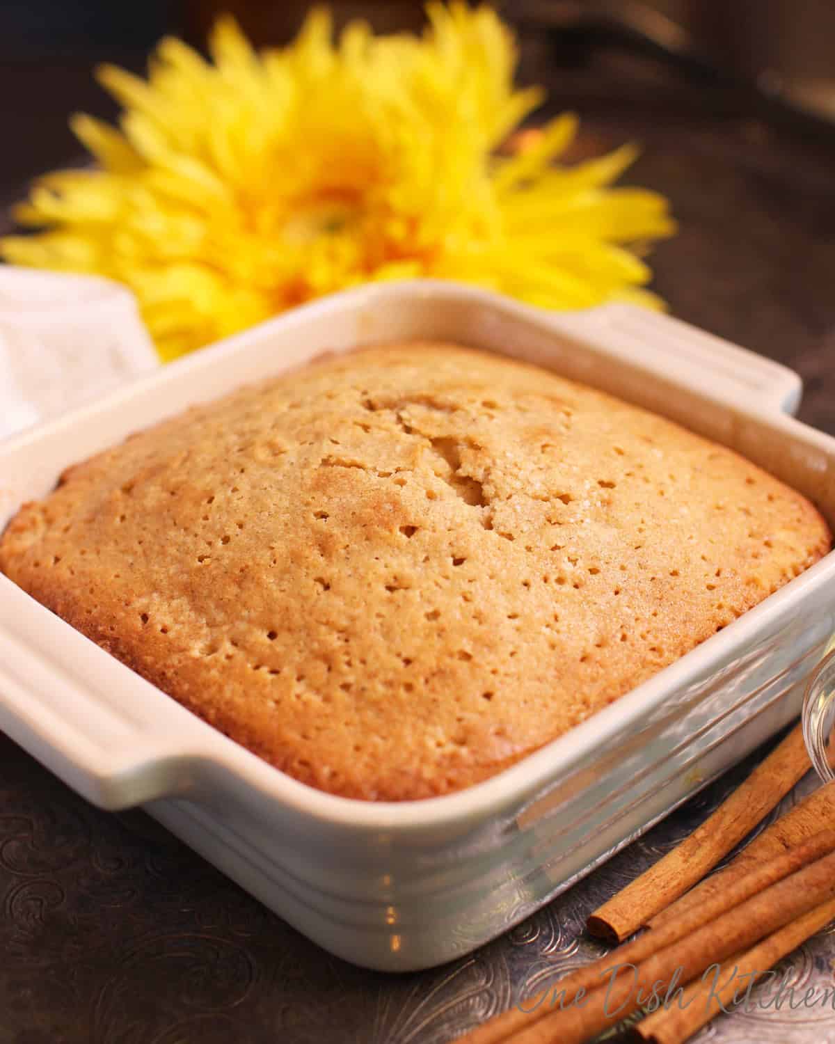 small spice cake on a silver tray next to cinnamon sticks.