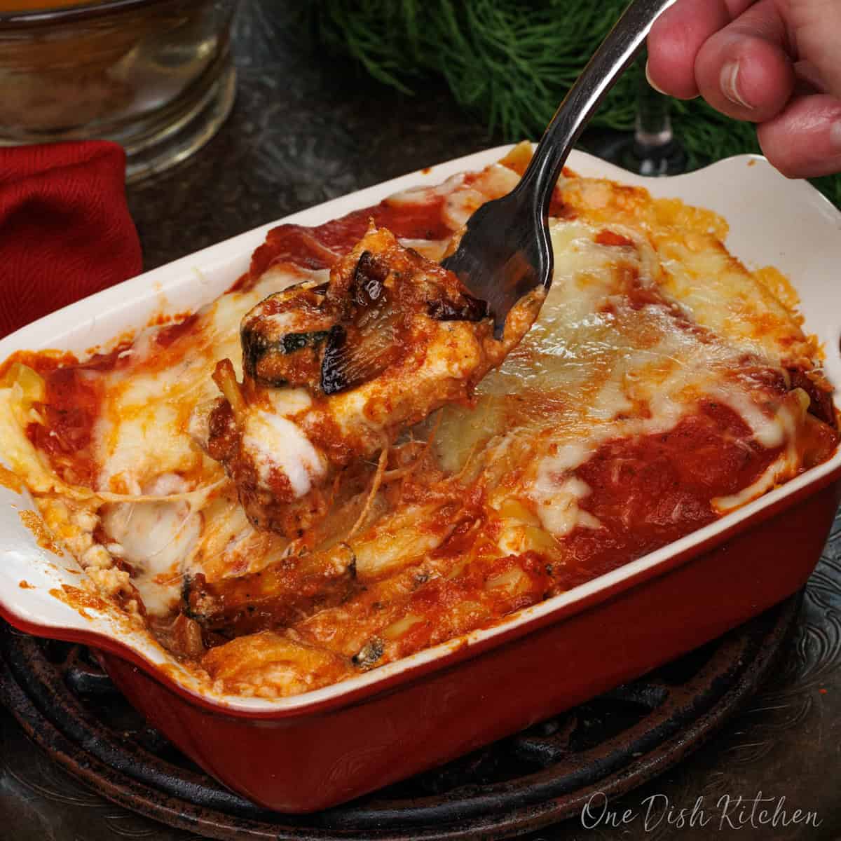 a small vegetable lasagna with a fork on the side of the dish.