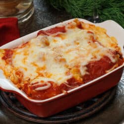 Vegetable lasagna in a small baking dish on a silver tray next to a glass of red wine