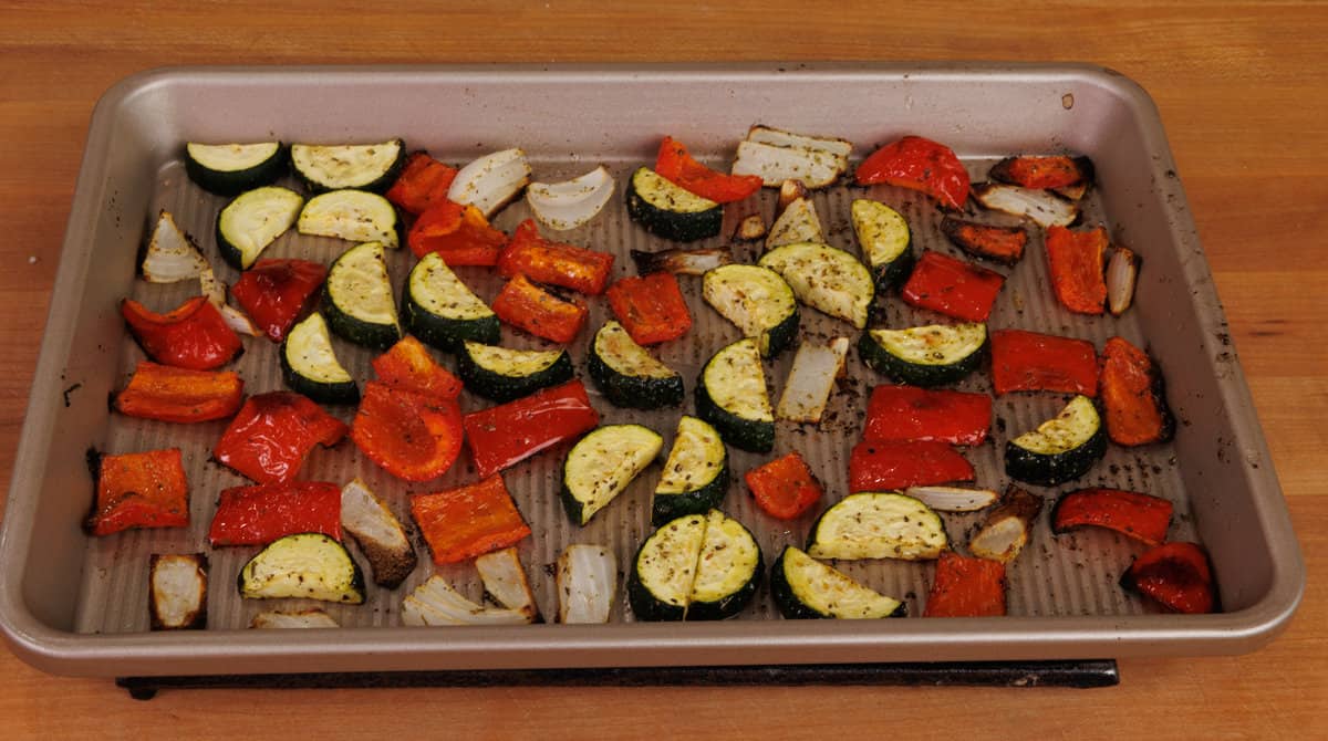roasted zucchini, red bell peppers, and onions on a baking sheet