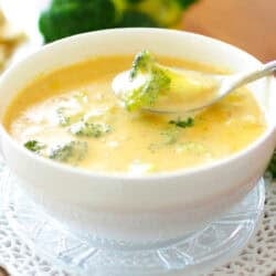 a single serving of broccoli cheddar soup with a spoon on the side.