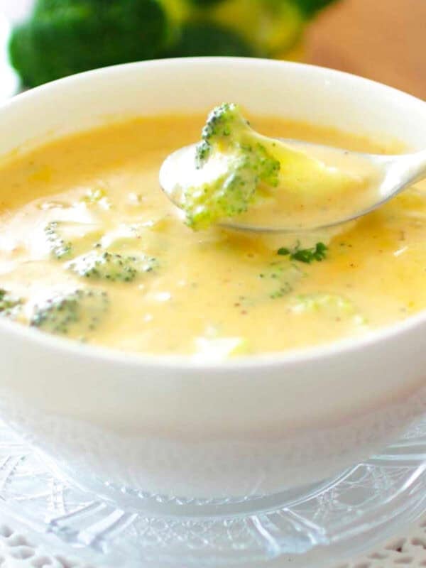 a single serving of broccoli cheddar soup with a spoon on the side.