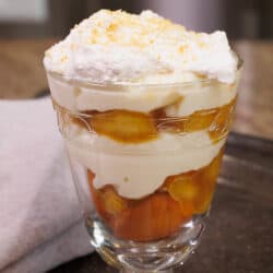 an old fashioned banana pudding made with caramelized bananas in a clear dessert glass next to a brown napkin