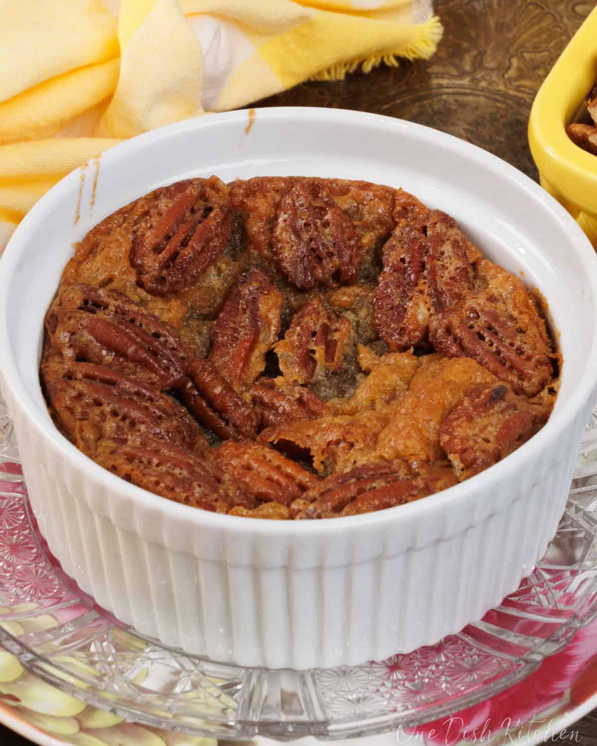 an individual crustless pecan pie on a pink plate next to a yellow napkin.