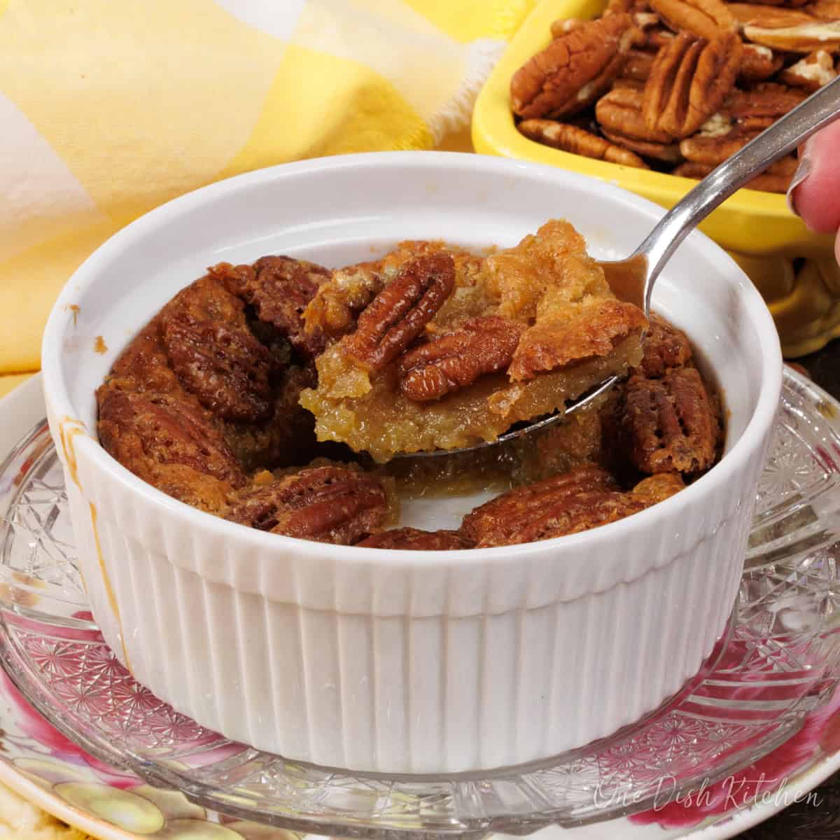 a small crustless pecan pie in a ramekin with a spoon on the side.