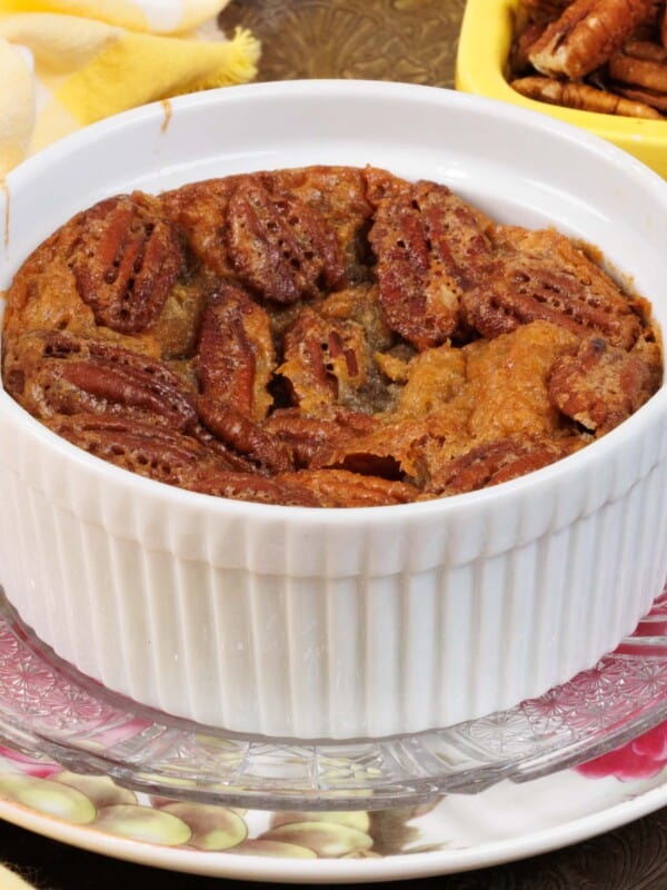a crustless maple pecan pie in a white baking dish next to a bowl of pecans