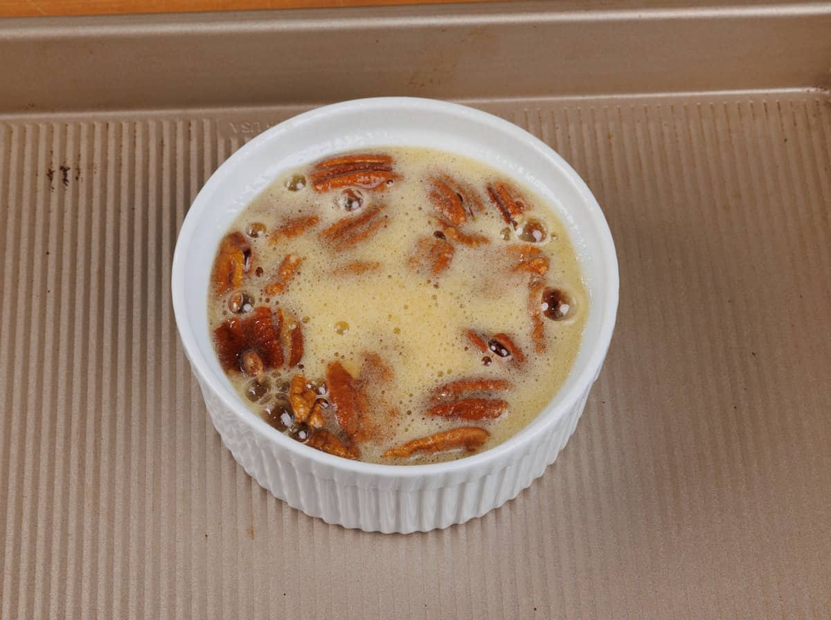 a mini pecan pie in a ramekin on a baking sheet