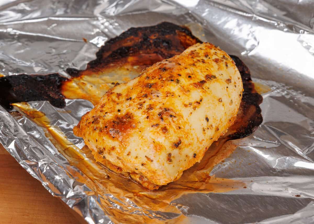 a marinated chicken breast on a baking sheet.