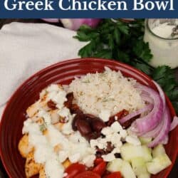 baked chicken topped with tzatziki sauce, olives, tomatoes, onions and feta in a red bowl.