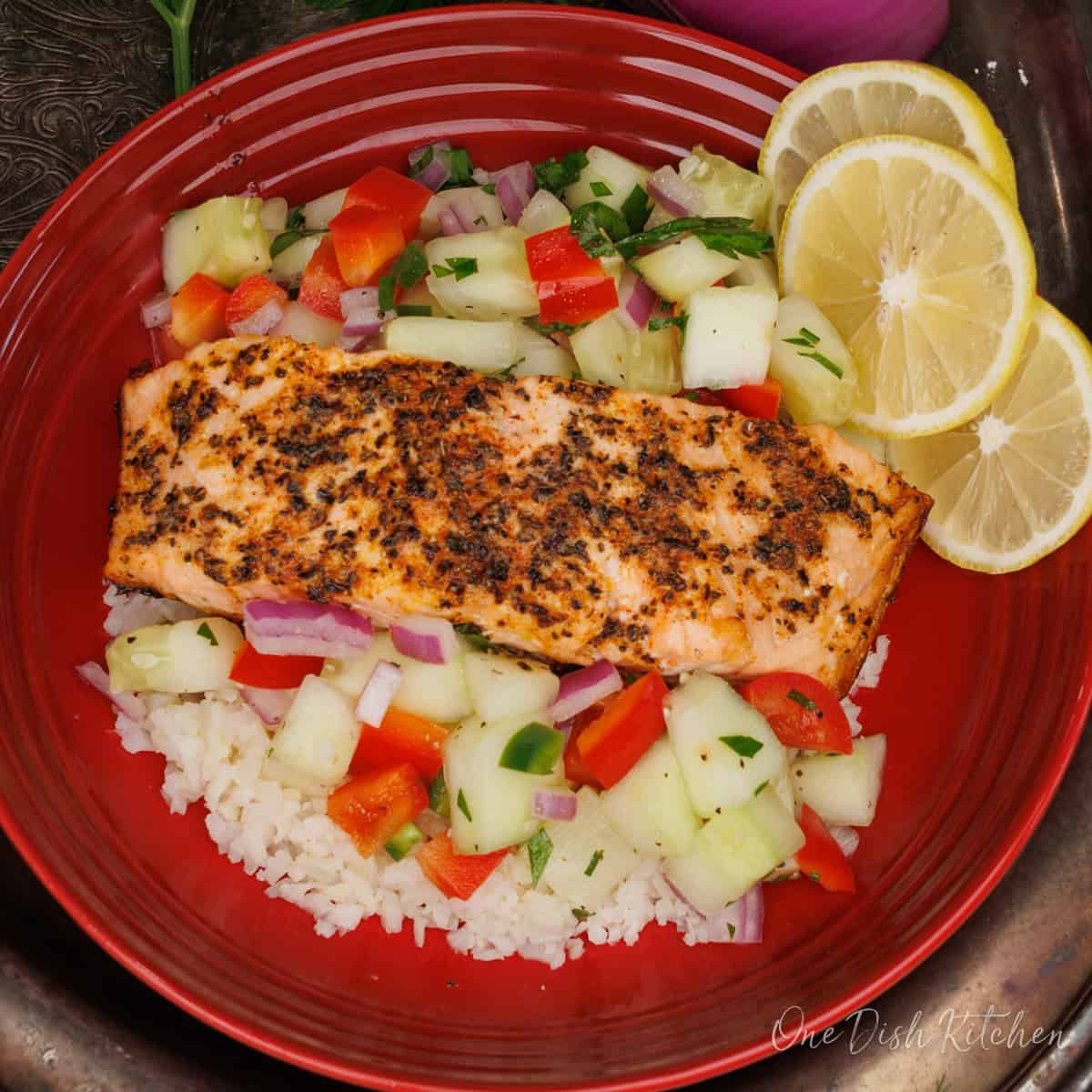 a red bowl filled with rice, salmon and salsa next to a red onion and fresh parsley.