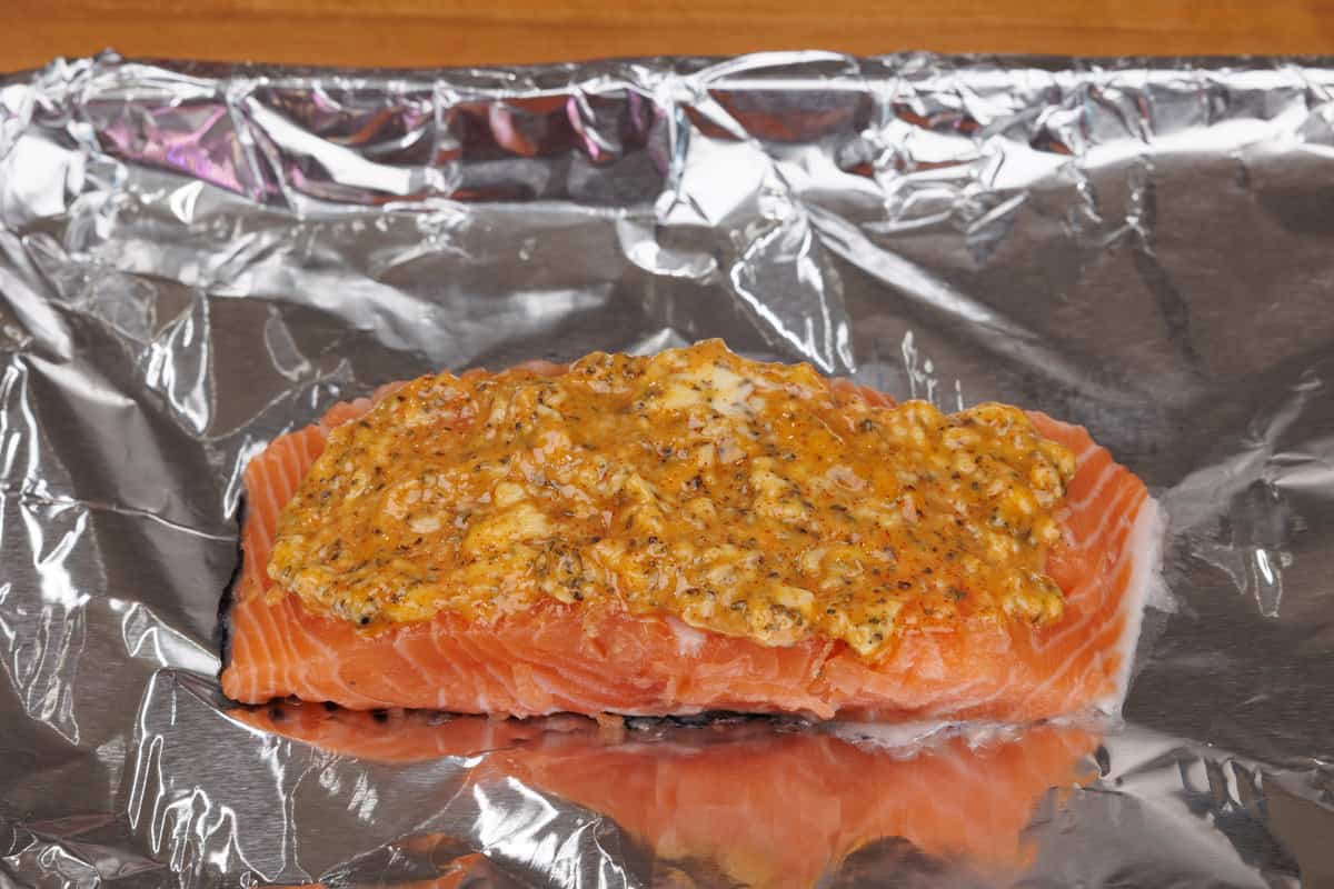 one salmon fillet on a baking sheet topped with softened butter and herbs