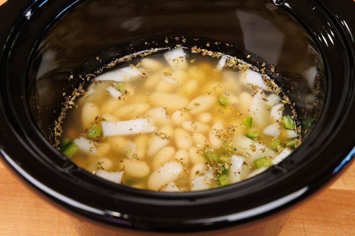 chicken, beans, onions, and broth in a slow cooker.