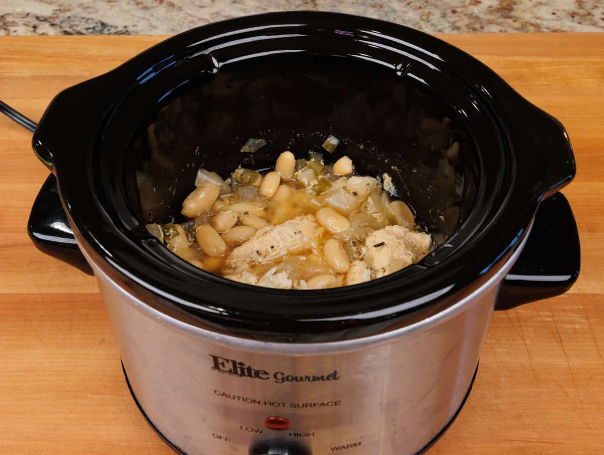 white chicken chili cooked in a crockpot with the chicken shredded