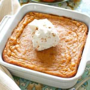 a small sweet potato pie in a square baking dish next to a plate of sliced sweet potatoes.
