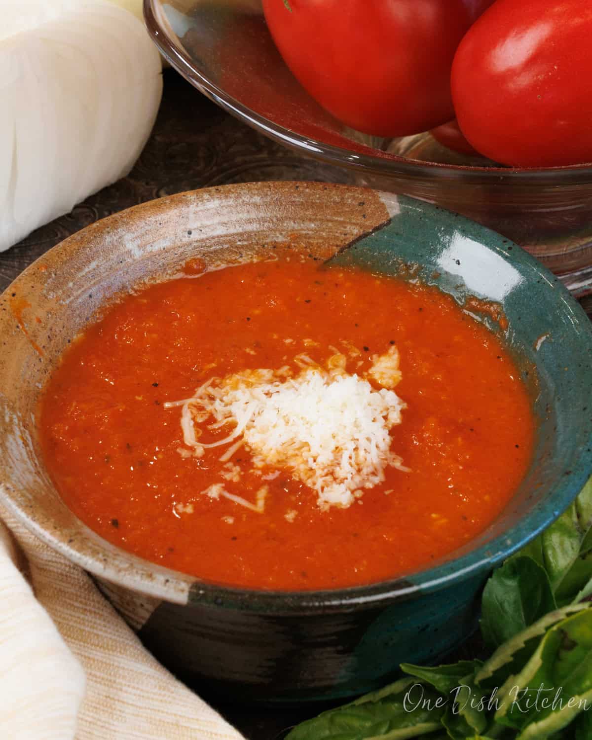 Tomato Soup in a bowl next to a bowl of fresh tomatoes.