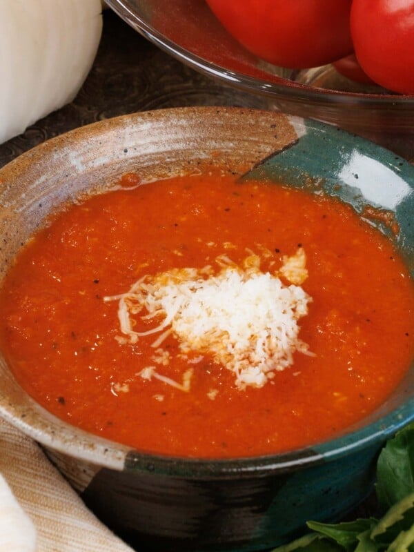 a bowl of homemade tomato basil soup topped with parmesan cheese on a silver tray