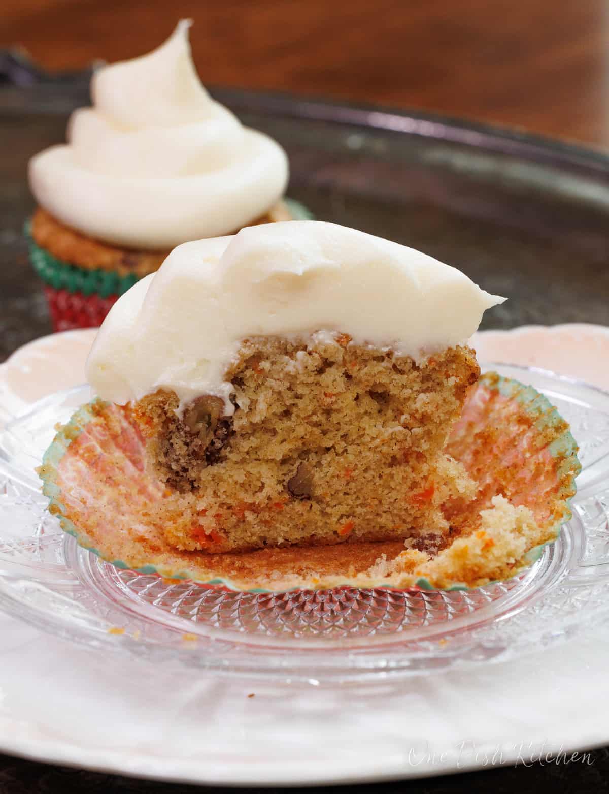 half of a carrot cake cupcake on a plate that rests on a silver tray