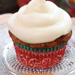 a carrot cake cupcake topped with cream cheese frosting on a white plate.