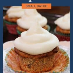 four carrot cake cupcakes with cream cheese frosting on a silver tray.