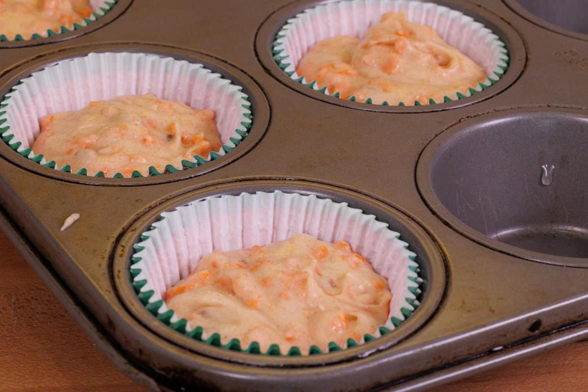 5 unbaked carrot cake cupcakes in a muffin tin