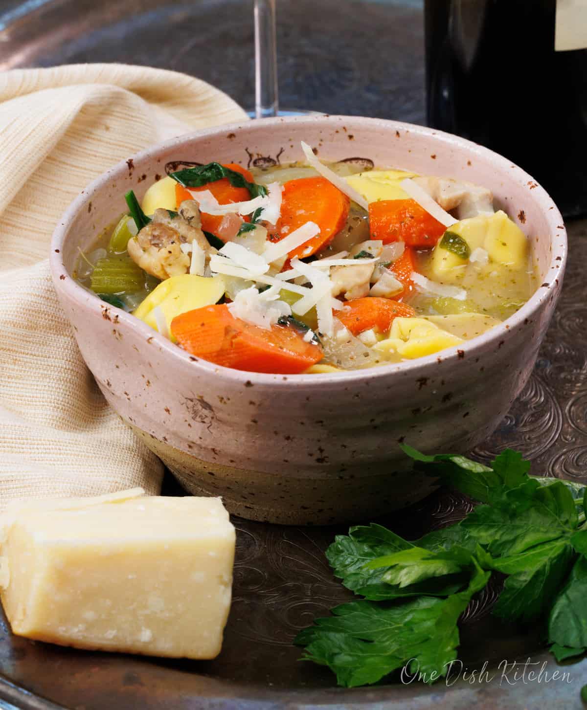 Chicken Tortellini Soup in a bowl shown with Parmesan cheese.