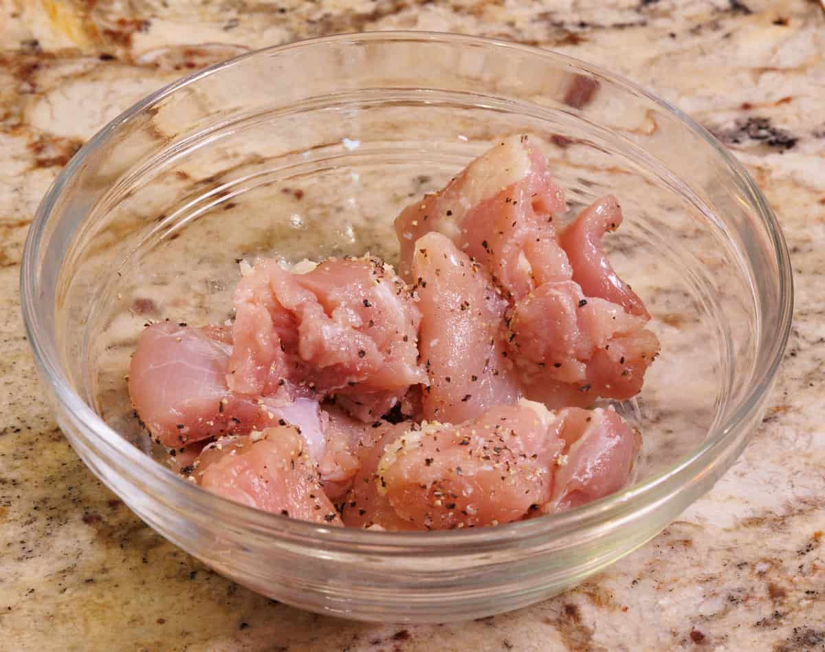pieces of raw chicken seasoned with salt and pepper in a small bowl