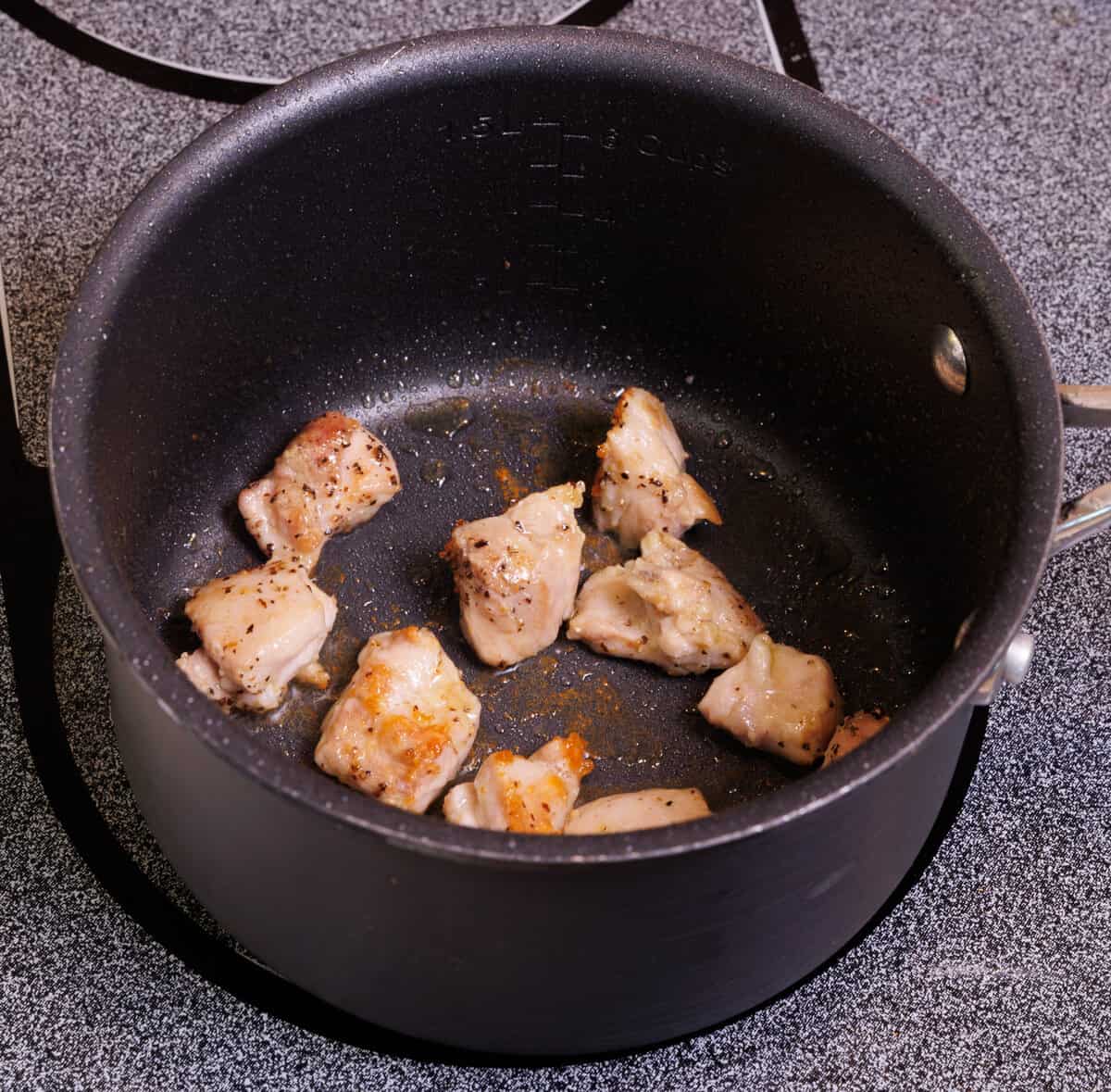 pieces of chicken cooking in a small pan