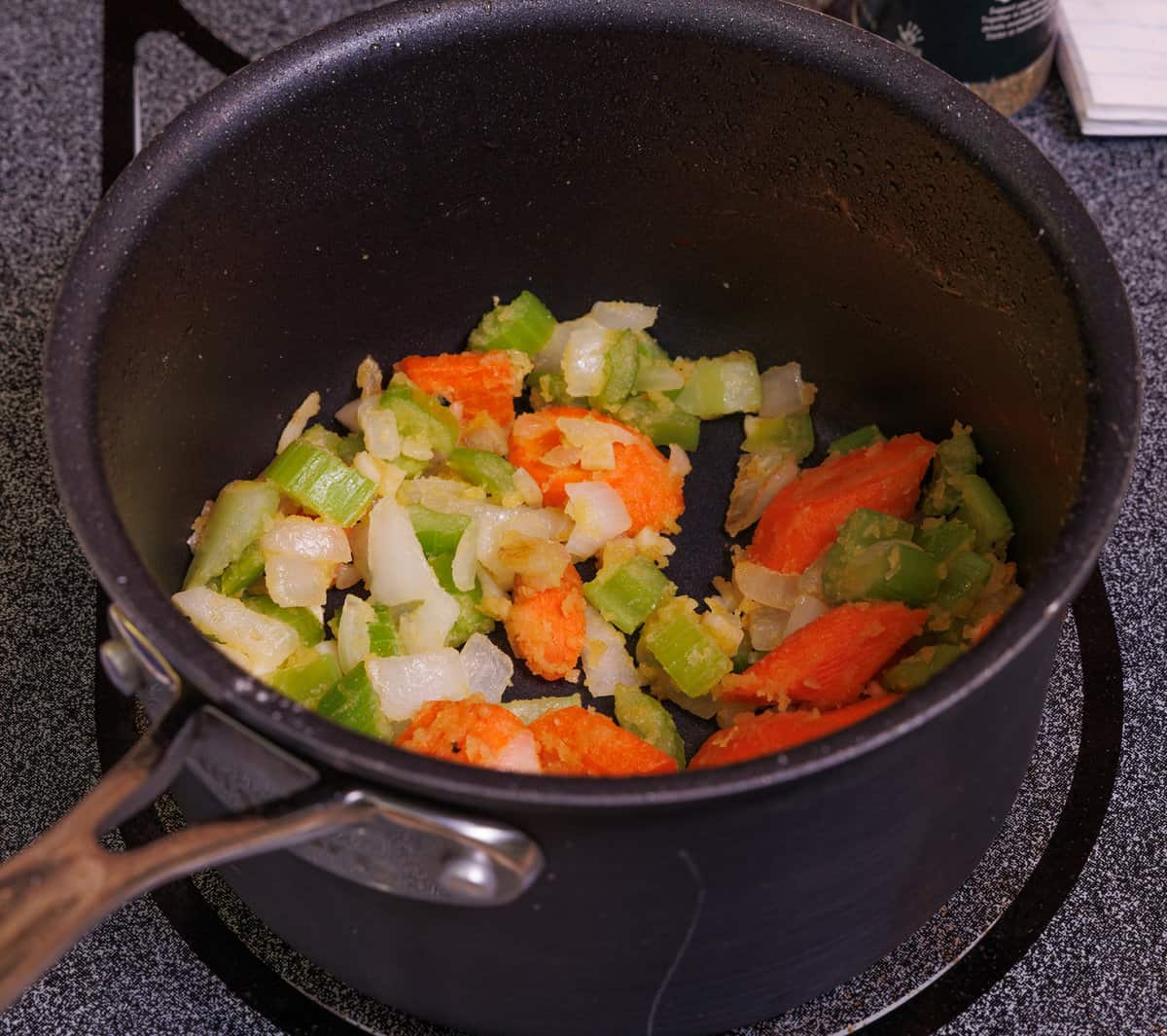 carrots, celery, onions, and garlic cooking in a small saucepan