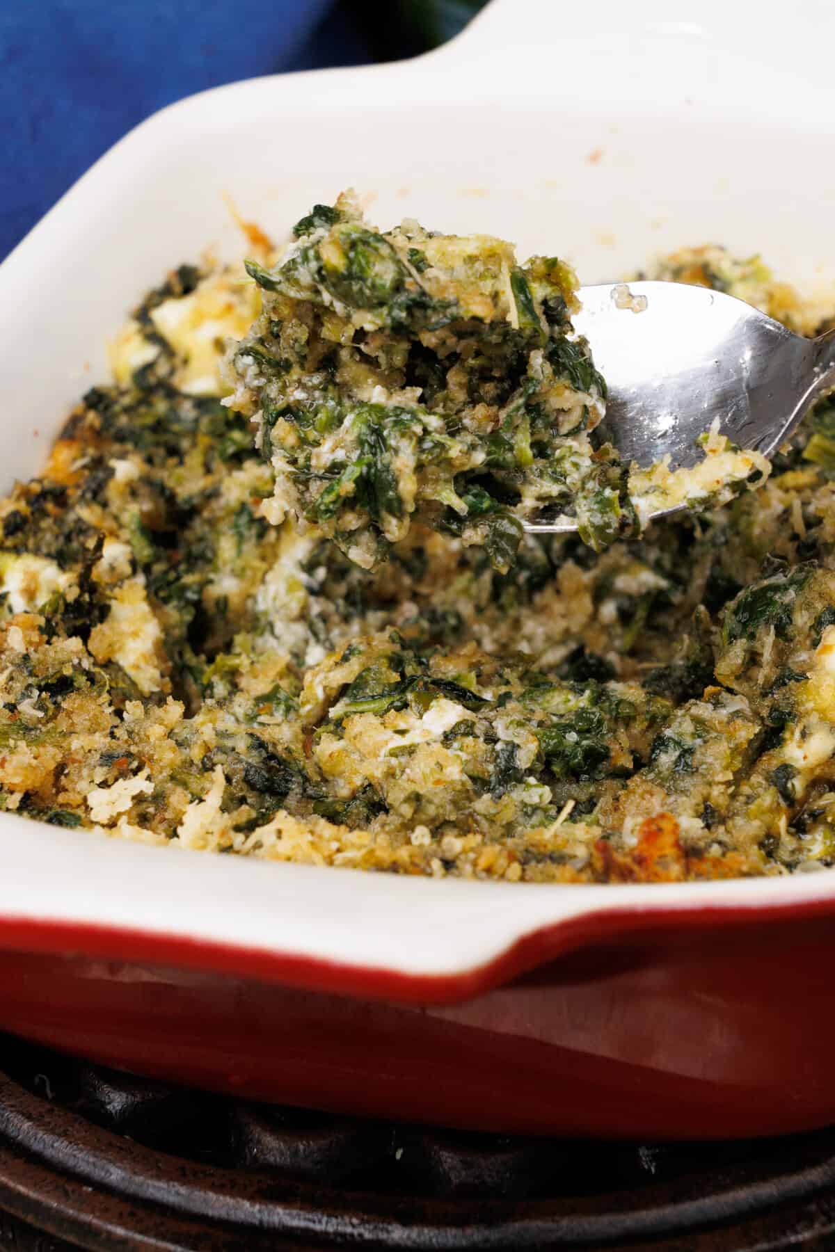 a small batch of creamy baked spinach in a red dish