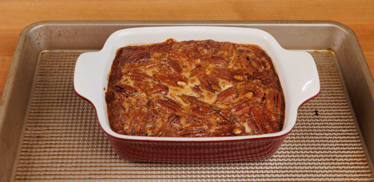 a small pecan pie in a red rectangular baking dish on a rimmed baking sheet