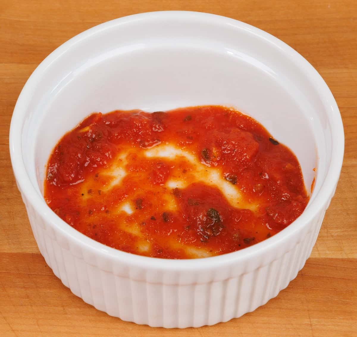 marinara sauce lining the bottom of a small ramekin