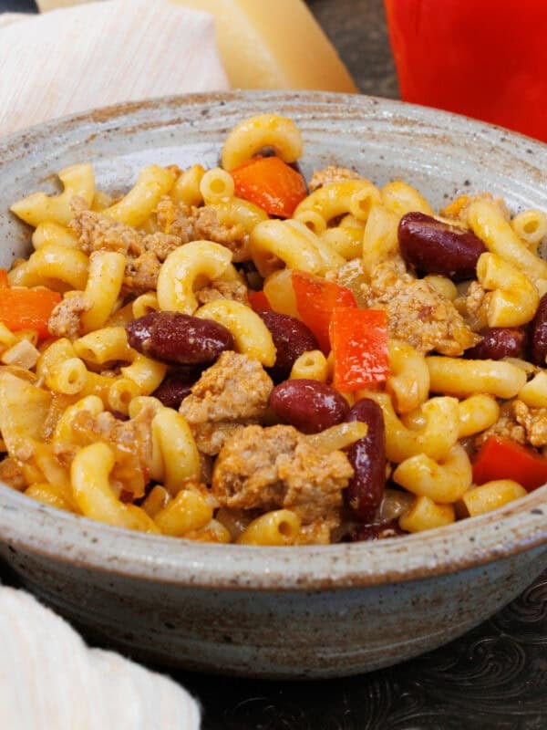 a bowl of chili mac next to a white napkin.