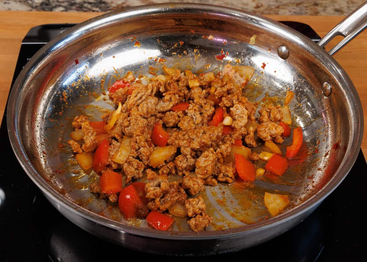 ground beef cooking in a skillet along with vegetables.