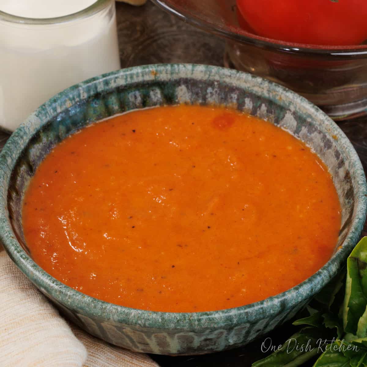 a small bowl of creamy tomato soup on a silver tray next to a brown napkin