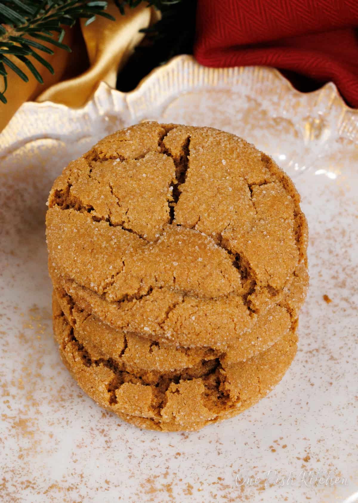  a stack of molasses cookies on top of each other on a white plate next to a red napkin and a gold napkin