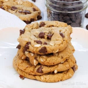 four oatmeal chocolate chip cookies stacked on a white plate.