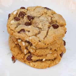 four oatmeal chocolate chip cookies on top of each other on a white plate